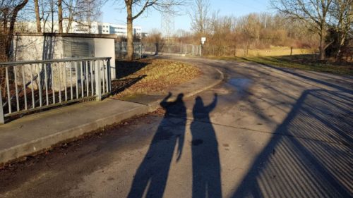 Zwei winkende Schatten auf einer Straße